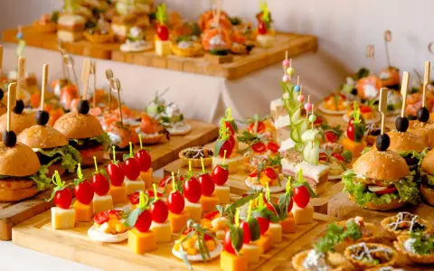 Buffet de petits fours variés : mini-burgers, toasts au saumon, brochettes de tomates et dés de fromage. Une belle idée pour une recette petit four réussie.