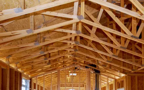 Structure complexe de charpente en bois, avec des fermes et des poutres formant un contreventement bois solide pour une nouvelle construction.