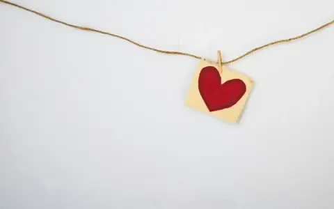 A red heart on a small fabric square, hung by a clothespin on a string. A simple symbol, asking: does God love everyone?