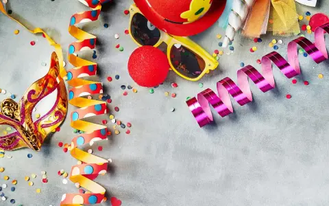 Karneval am Donnerstag: Goldene Maske, bunte Luftschlangen, rote Clownsnase und Konfetti laden zum Feiern ein.