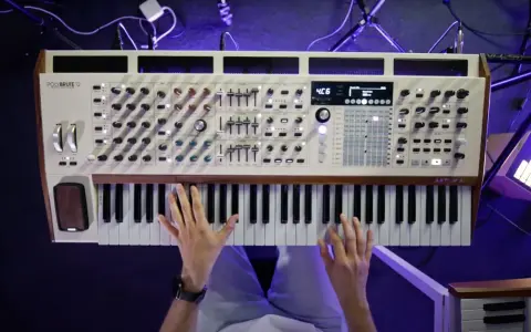 Ręce grają na syntezatorze Arturia PolyBrute 12. Widać pokrętła, suwaki i klawisze, tworząc bogate **music stems**.