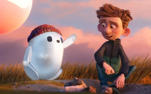 Chłopiec i robot Ron, bohater jednej z warner bros bajek, siedzą na wzgórzu podczas zachodu słońca.