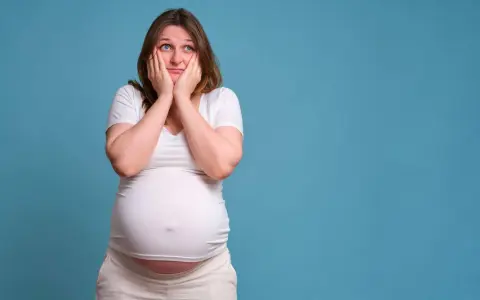 Donna incinta con le mani sul viso esprime paura in gravidanza, preoccupata per il futuro.