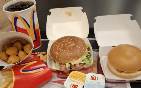 Zestaw McDonald's: burger, frytki, nuggetsy, napój i sosy.