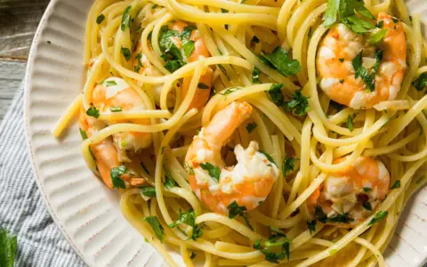 Un piatto invitante di pasta con gamberetti, condita con prezzemolo fresco e un filo d'olio.