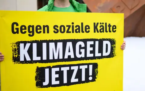 Gelbe Tafel mit schwarzer Schrift: "Gegen soziale Kälte KLIMAGELD JETZT!". Eine Forderung nach sozialer Gerechtigkeit im Klimaschutz.