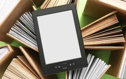 Un e-reader con schermo bianco è circondato da libri aperti, pronti per essere letti.