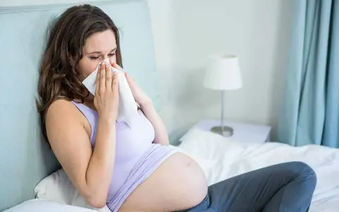 Donna incinta con raffreddore, cerca sollievo con un fazzoletto. La scelta di un antistaminico in gravidanza richiede attenzione.
