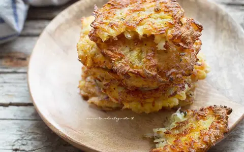 Una pila di dorate frittelle di patate su un piatto di legno. Croccanti fuori, morbide dentro, perfette per uno spuntino.