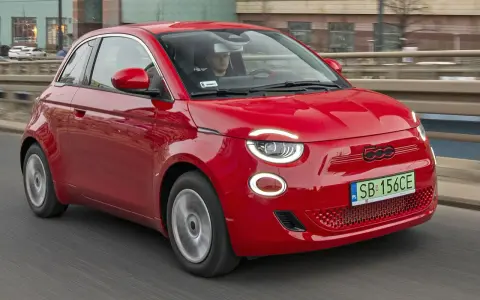 Czerwony Fiat 500 jedzie po drodze. Sprawdź aktualną fiat 500 cena i dowiedz się więcej o tym stylowym samochodzie.