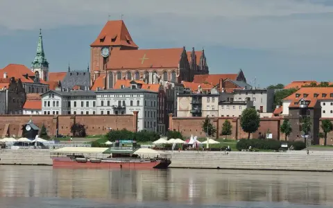Widok na średniowieczny zespół miejski Torunia z Wisły. W oddali katedra i kamienice, na pierwszym planie barka.