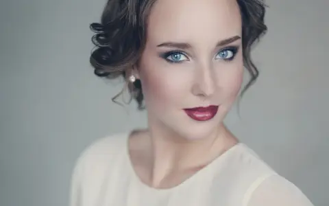 Maquillaje para vestido blanco: ojos ahumados y labios rojos intensos, peinado recogido con rizos.