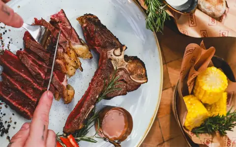 Idealne jakie wino do steka? Soczysty stek T-bone z pieczonymi kolbami kukurydzy i sosem.