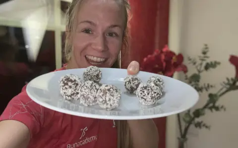 Glad kvinna visar upp en tallrik med hemgjorda chokladbollar, perfekta för ett snabbt och enkelt chokladbollar recept.
