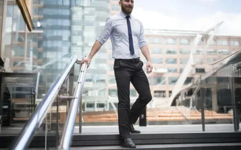 Uomo con pantaloni neri come abbinarli: camicia azzurra e cravatta blu, un look da ufficio moderno.