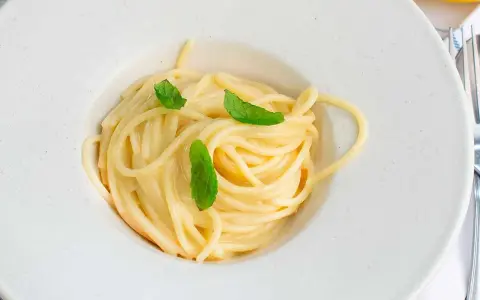 En krämig pasta limone, serverad i en vit skål med färska myntablad.