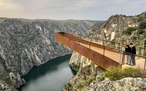 Pareja admira el paisaje desde el mirador del fraile, una pasarela metálica que se adentra en un cañón con un río.
