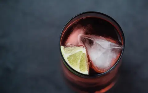 Czerwony drink z lodem i limonką. Idealny do degustacji z brandy Kazbek Peak, odkryj nowe smaki!