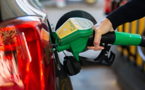 Tankstelle: Eine Hand betankt ein Auto mit dem grünen Zapfhahn. So behältst du im Blick, wie viel verbraucht dein Auto.