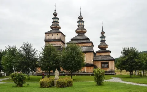 Drewniana cerkiew z trzema kopułami, otoczona zielenią. Wspaniałe krempna atrakcje dla miłośników historii i architektury.