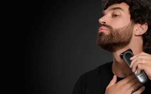 Hombre con barba cola de pato, perfil, usando una recortadora Braun para definir su estilo.