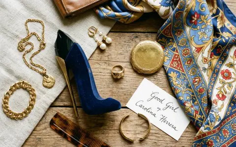 Elegancki zestaw: perfumy damskie bucik, złota biżuteria, jedwabna apaszka i brązowy portfel.