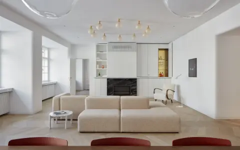 Un moderno sofá en medio del salón, con chimenea y estanterías integradas.