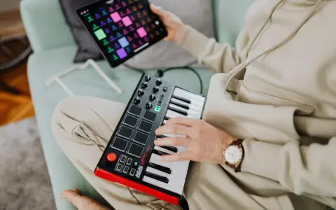 Osoba tworzy muzykę na kontrolerze midi usb. To świetny sposób na rozpoczęcie przygody z produkcją muzyczną.