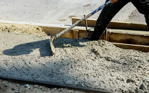 Pracownik rozprowadza świeży beton B25. Czas wiązania betonu zależy od wielu czynników.