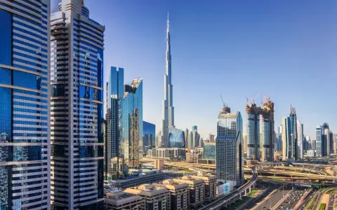 Nowoczesne wieżowce Dubaju, w tym Burj Khalifa, na tle błękitnego nieba. Widać autostrady i linie lotnicze Dubaj.