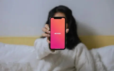Dłoń trzyma telefon z logo Tindera. Zastanawiasz się, czemu nie mogę usunąć konta na Tinderze?
