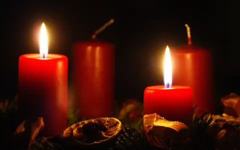 Two red candles glow, marking the 2nd advent. A festive wreath with dried orange slices and pine needles surrounds them.