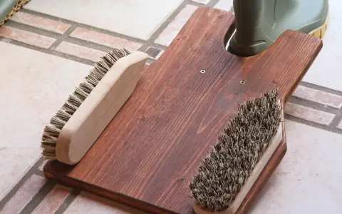 Selbstgebauter Bootsanker aus Holz mit zwei Bürsten und einem grünen Stiefel.