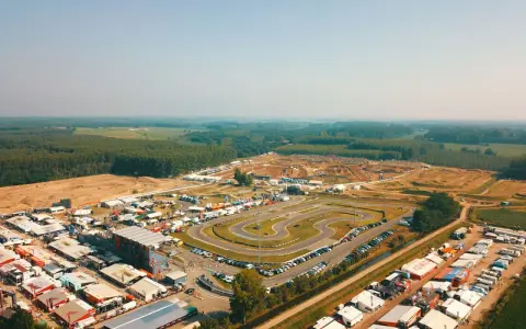 Vista aerea di un circuito **ottobiano motorsport** con paddock, tribune e pista da cross sullo sfondo, immerso nel verde.
