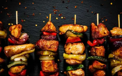 Spiedini di carne succulenti e colorati, alternati a cipolle, peperoni e zucchine, pronti per essere gustati.