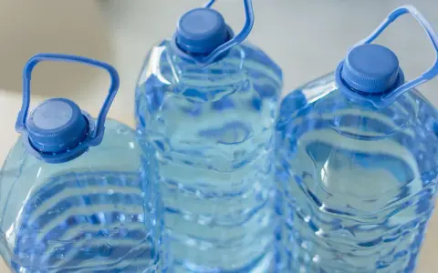 Trzy duże, niebieskie butelki z wodą, każda z uchwytem. Zastanawiasz się, ile może stać woda w plastikowej butelce po otwarciu?