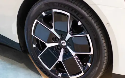 Pneu Michelin sur jante noire et argentée avec logo Mi sur une voiture blanche.