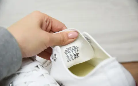 Dłoń pokazuje metkę z rozmiarem na białych butach Converse. Sprawdzamy, czy to oryginalne Converse, a nie podróbki.