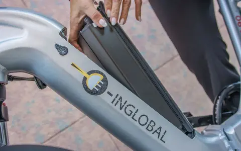 Mani che inseriscono la batteria in una bici elettrica. La durata della batteria di una bici elettrica è fondamentale per l'autonomia.
