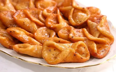 Plato de pestiños antiguos, dorados y brillantes, con un glaseado que los hace irresistibles. Perfectos para acompañar un café.