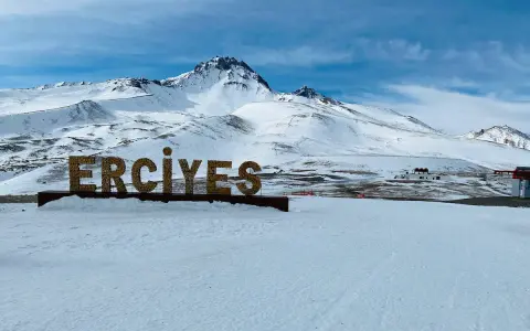 Zimowy krajobraz z napisem "ERCIYES" na tle ośnieżonych gór. Idealne miejsce na narty w Erciyes Ski Resort.