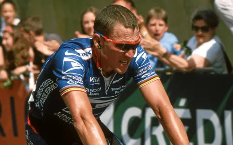 Lance Armstrong, in his USPS jersey, strains during a race, a stark image given how Lance Armstrong cheated his way to victory.