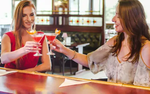 Dwie przyjaciółki wznoszą toast drinkami w barze. Idealny weekend z przyjaciółką!