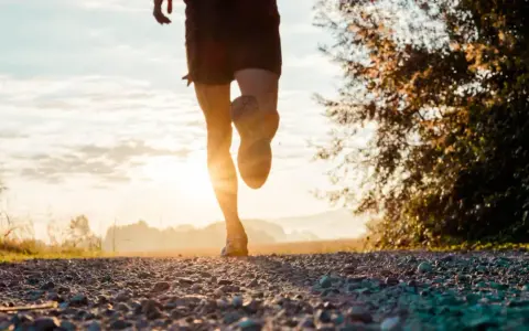 Gambe di un corridore su un sentiero sterrato al tramonto. Ottimo per bruciare calorie corsa 7 km/h.