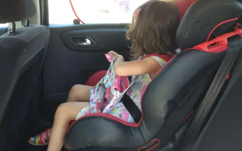 Niña en silla de coche, lista para el viaje. Aún no es el momento cuando puede ir un niño sin silla en el coche.