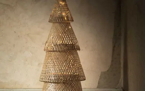 Un sapin de Noël en tissu à faire soi-même, fait de cônes tressés et illuminé de guirlandes lumineuses.