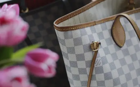 Jasna torebka Louis Vuitton w kratkę Damier Azur z różowymi tulipanami w tle.