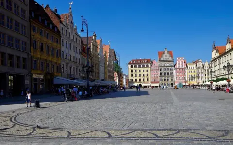 Kolorowy Rynek we Wrocławiu, idealne miejsce na jednodniowe wycieczki z Wrocławia. Ludzie spacerują, siedzą w kawiarniach, ciesząc się słońcem.