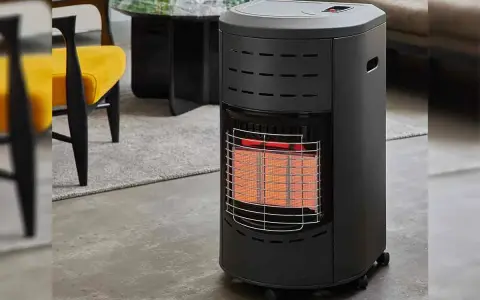 Chauffage d'appoint gaz danger : appareil noir avec grille métallique devant des éléments chauffants rouges, dans un salon moderne.