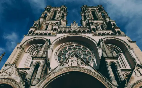 La **cathédrale de Laon**, majestueuse et imposante, se dresse sous un ciel bleu profond. Ses tours jumelles et sa rosace ornée captivent le regard.
